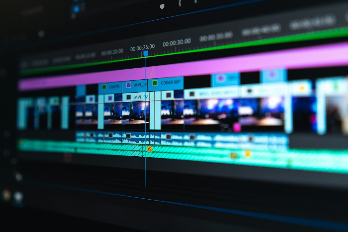 Na obrazovce počítače je vidět software pro střih videa s barevnými časovými osami.