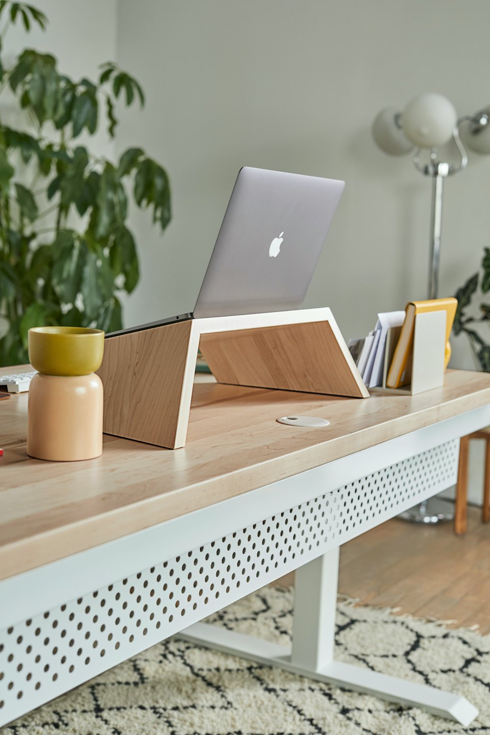 Notebook na světlém dřevěném stojanu na moderním stole.
