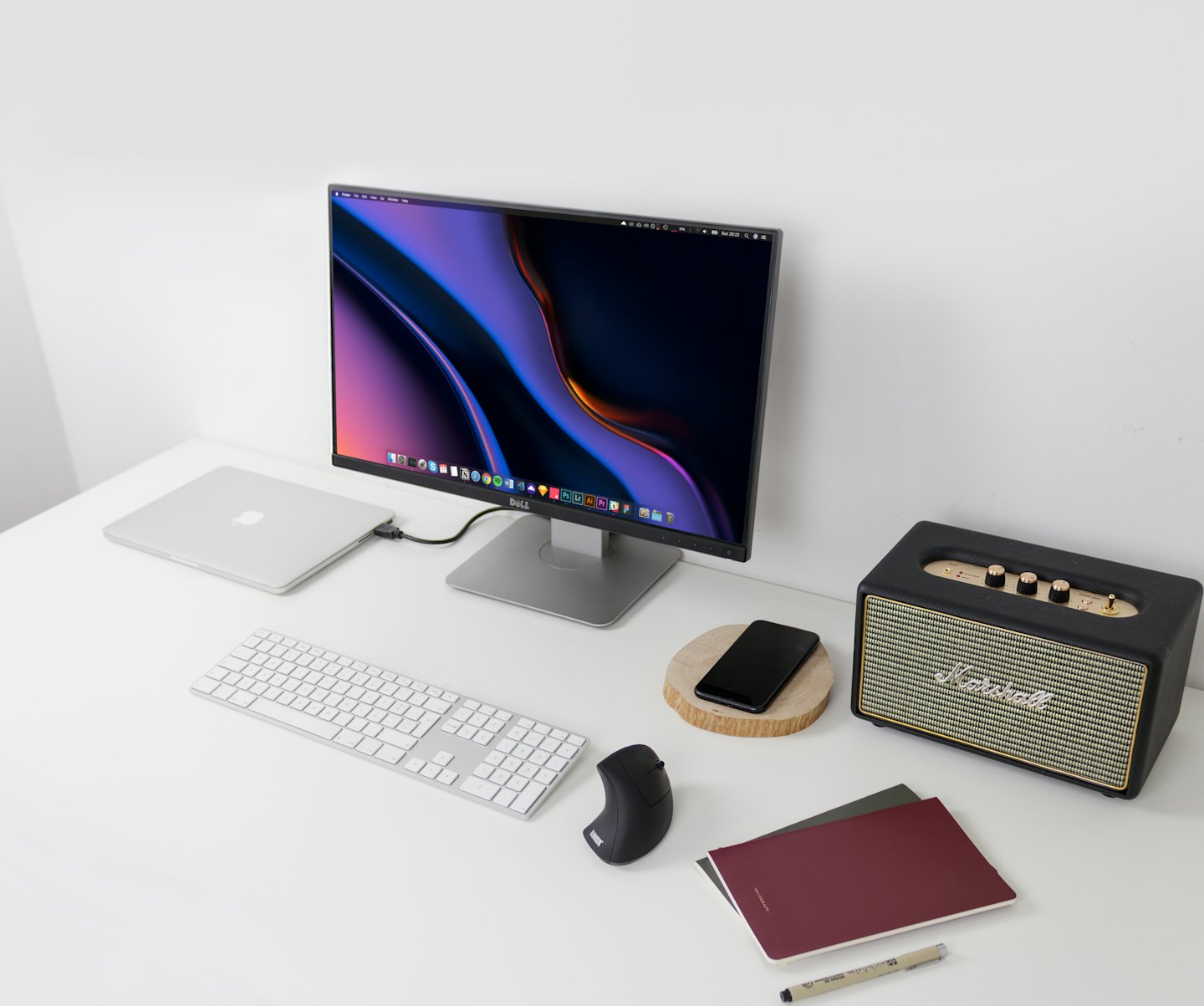 Moderní pracovní stůl s notebookem, monitorem, klávesnicí a reproduktorem.